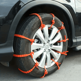 Oranje SnowGrip sneeuwkettingen gemonteerd op autoband, zorgt voor extra grip tijdens winterse omstandigheden.